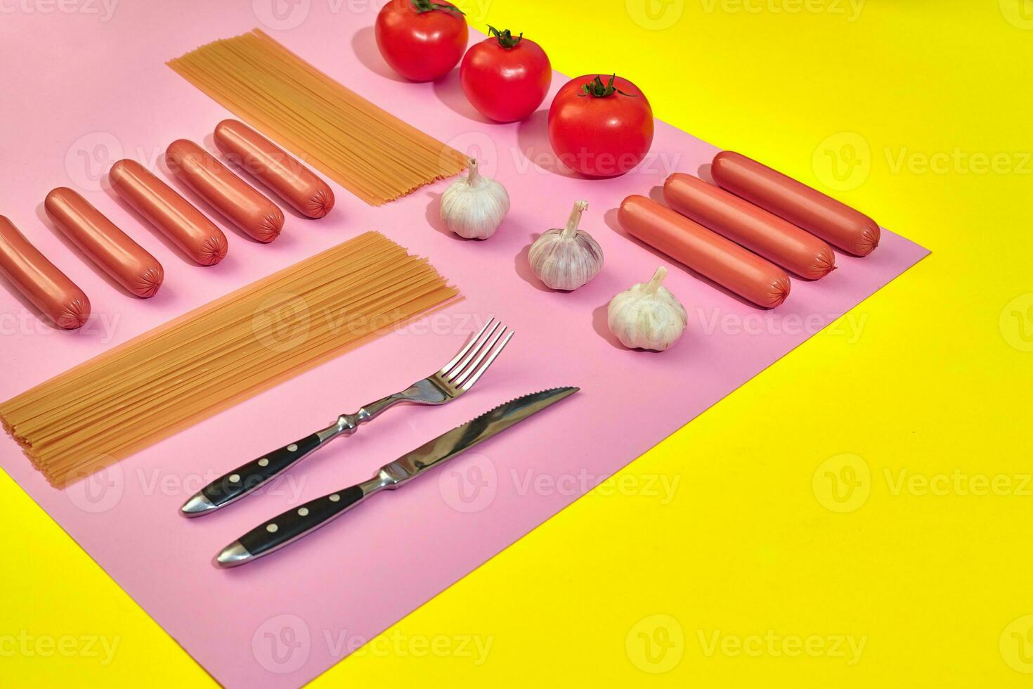 A lot of raw sausages with pasta and vegetables on pink and yellow background, top view. photo