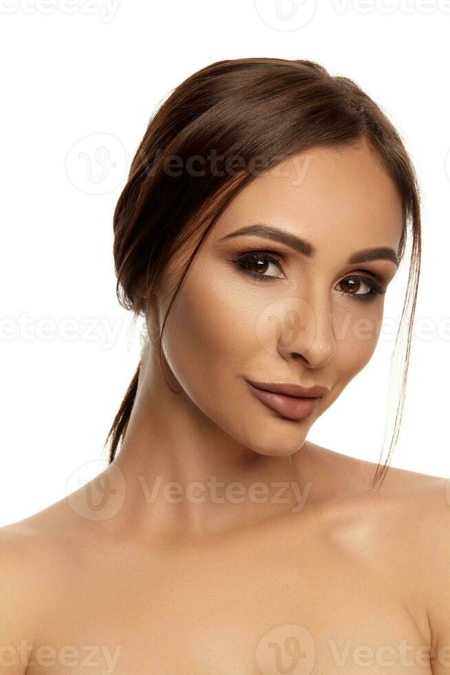 Close up portrait of a brunette nude model girl with professional evening make-up and plump lips, posing isolated on white background. photo