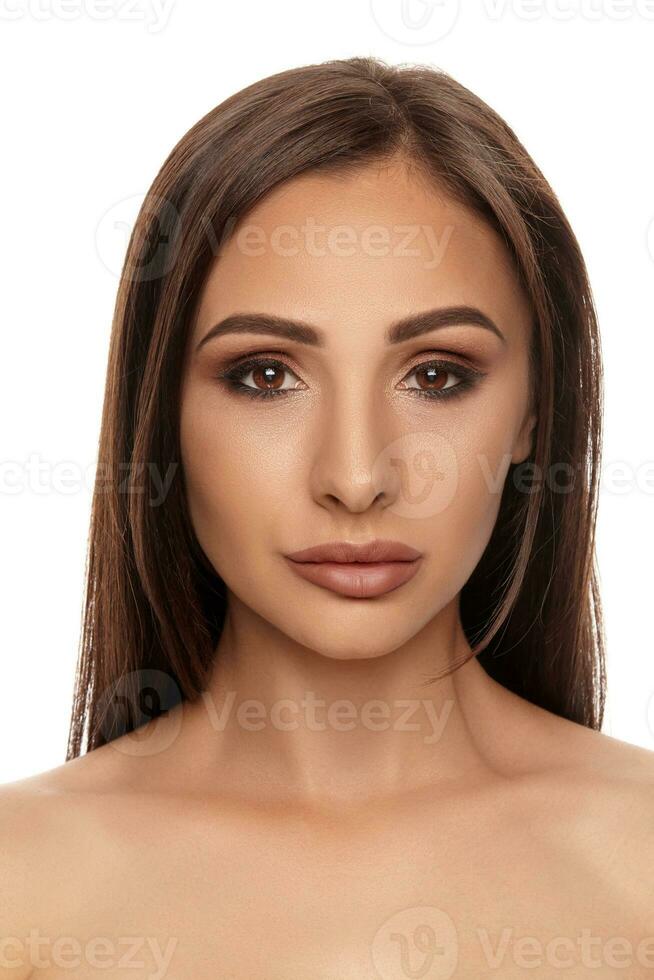 Close up portrait of a brunette nude model girl with professional evening make-up and plump lips, posing isolated on white background. photo