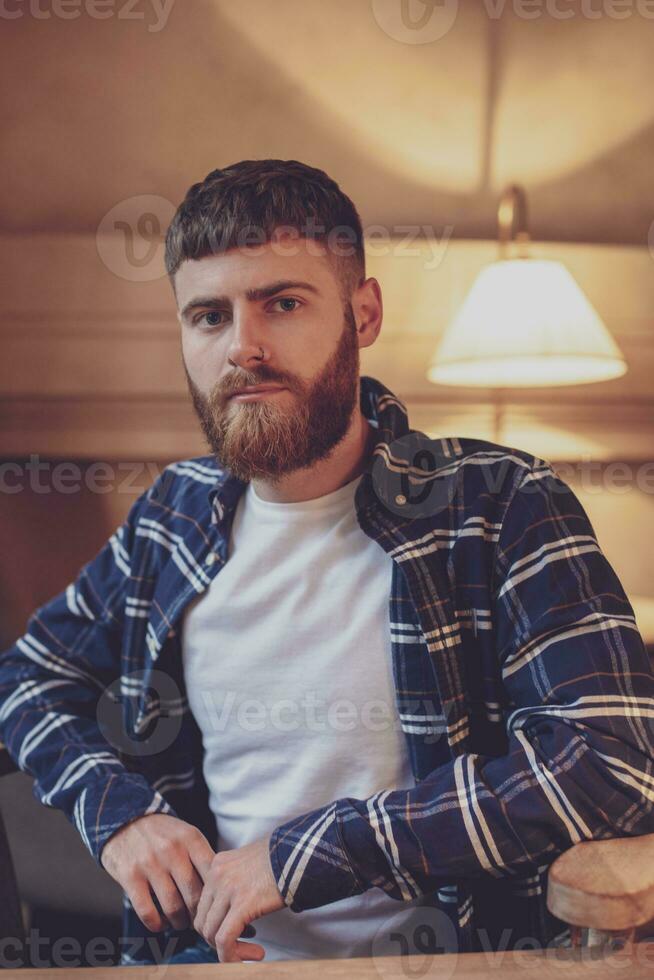 Portrait handsome bearded man wearing plaid shirt at modern cafe photo