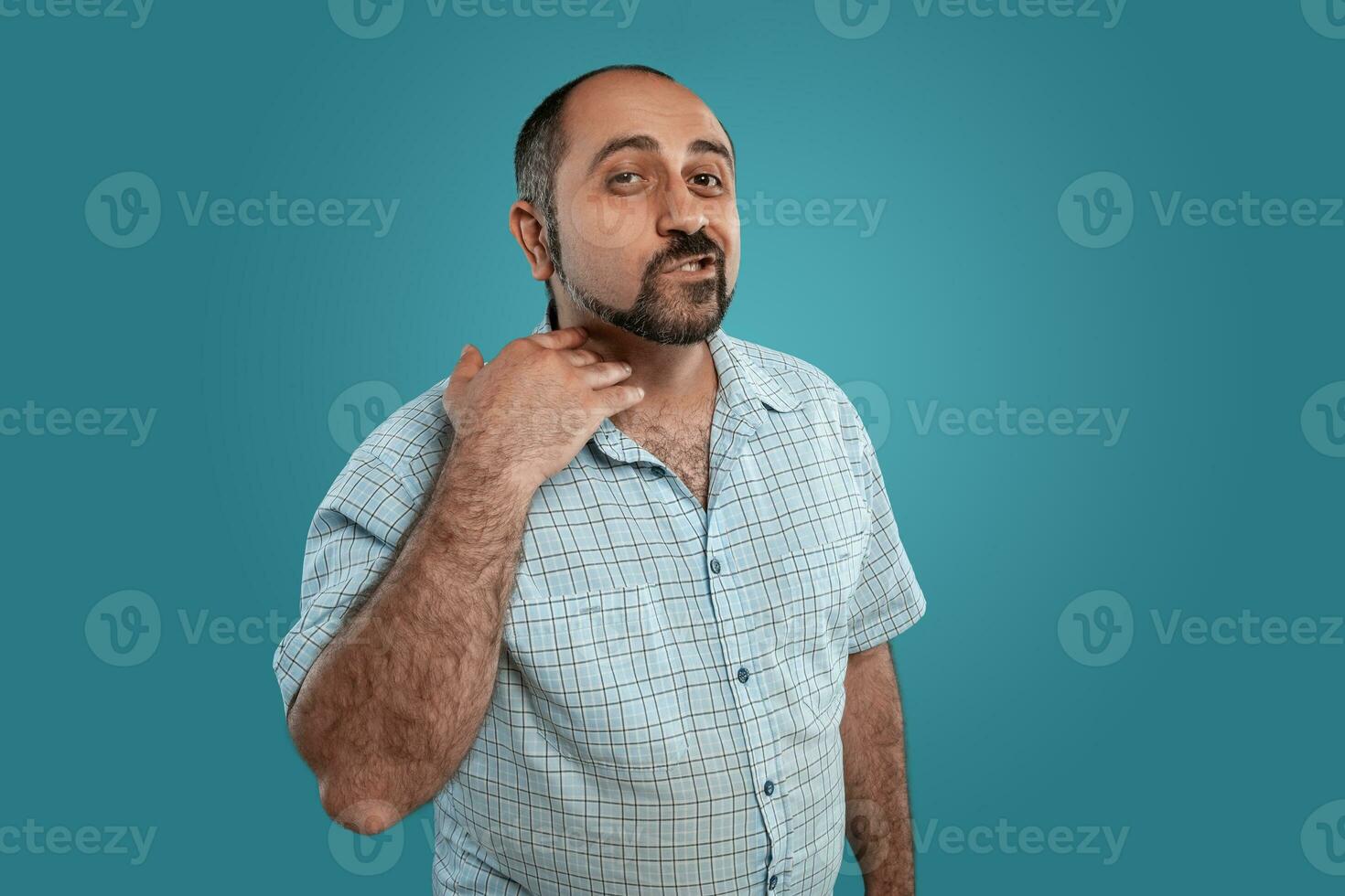 Close-up portrait of a brunet middle-aged man with beard, dressed in a light checkered shirt and posing against a blue background. photo