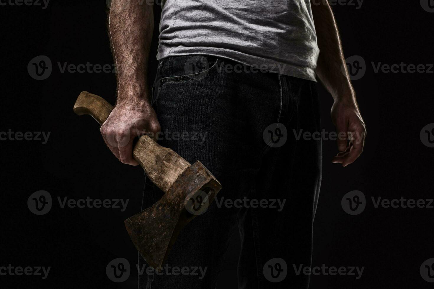 A man holds an ax in his hands against on black background photo