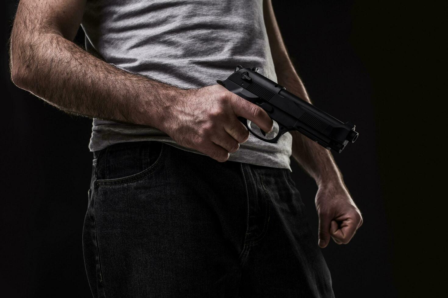 Killer with gun on black background at the studio photo