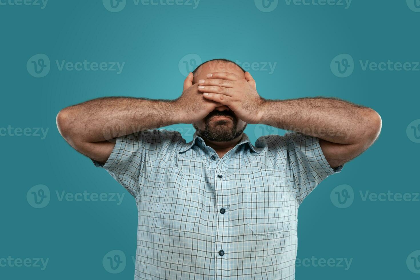 de cerca retrato de un moreno de edad mediana hombre con barba, vestido en un ligero a cuadros camisa y posando en contra un azul antecedentes. foto