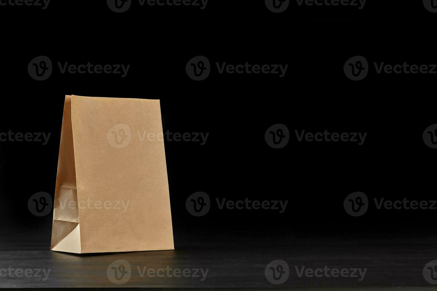 Eco friendly disposable tableware standing on dark surface against black background. Biodegradable craft dishes. Recycling concept. Close-up shot. photo