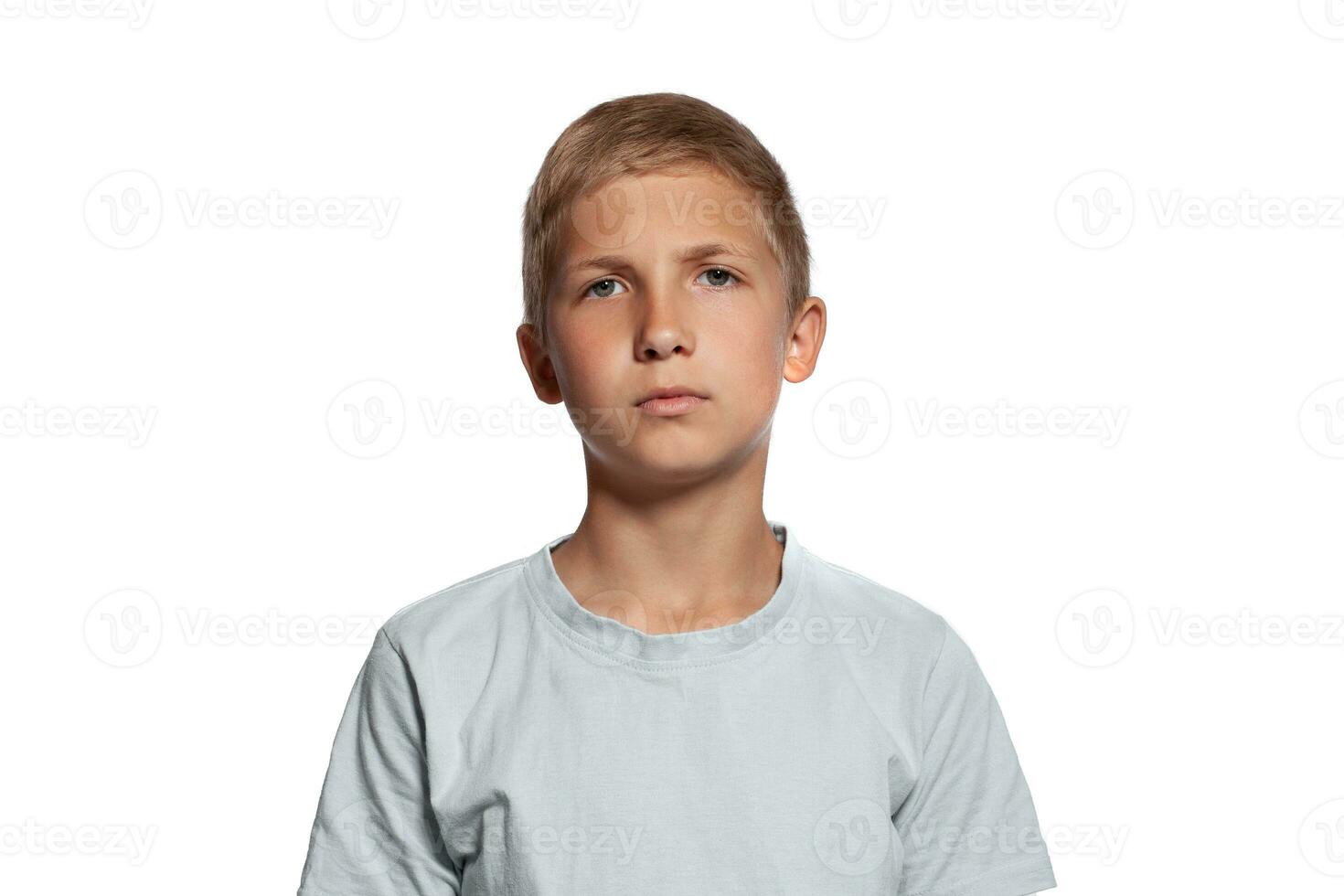 Close-up portrait of a blonde teenage boy in a white t-shirt posing isolated on white studio background. Concept of sincere emotions. photo