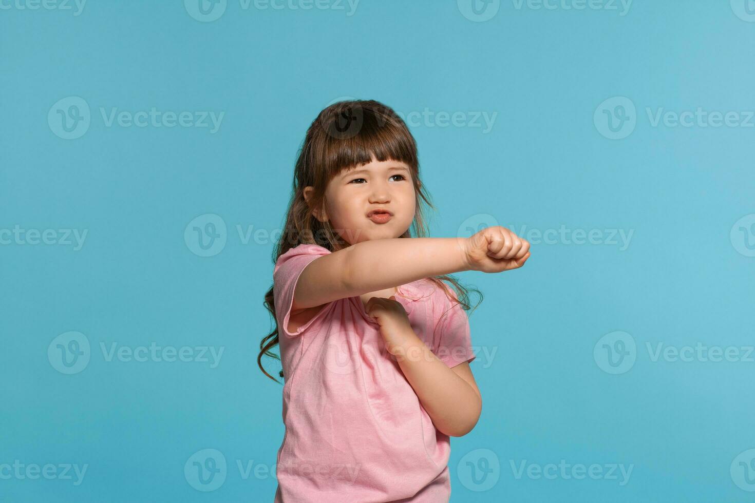 hermosa pequeño niña vistiendo en un rosado camiseta es posando en contra un azul estudio antecedentes. foto