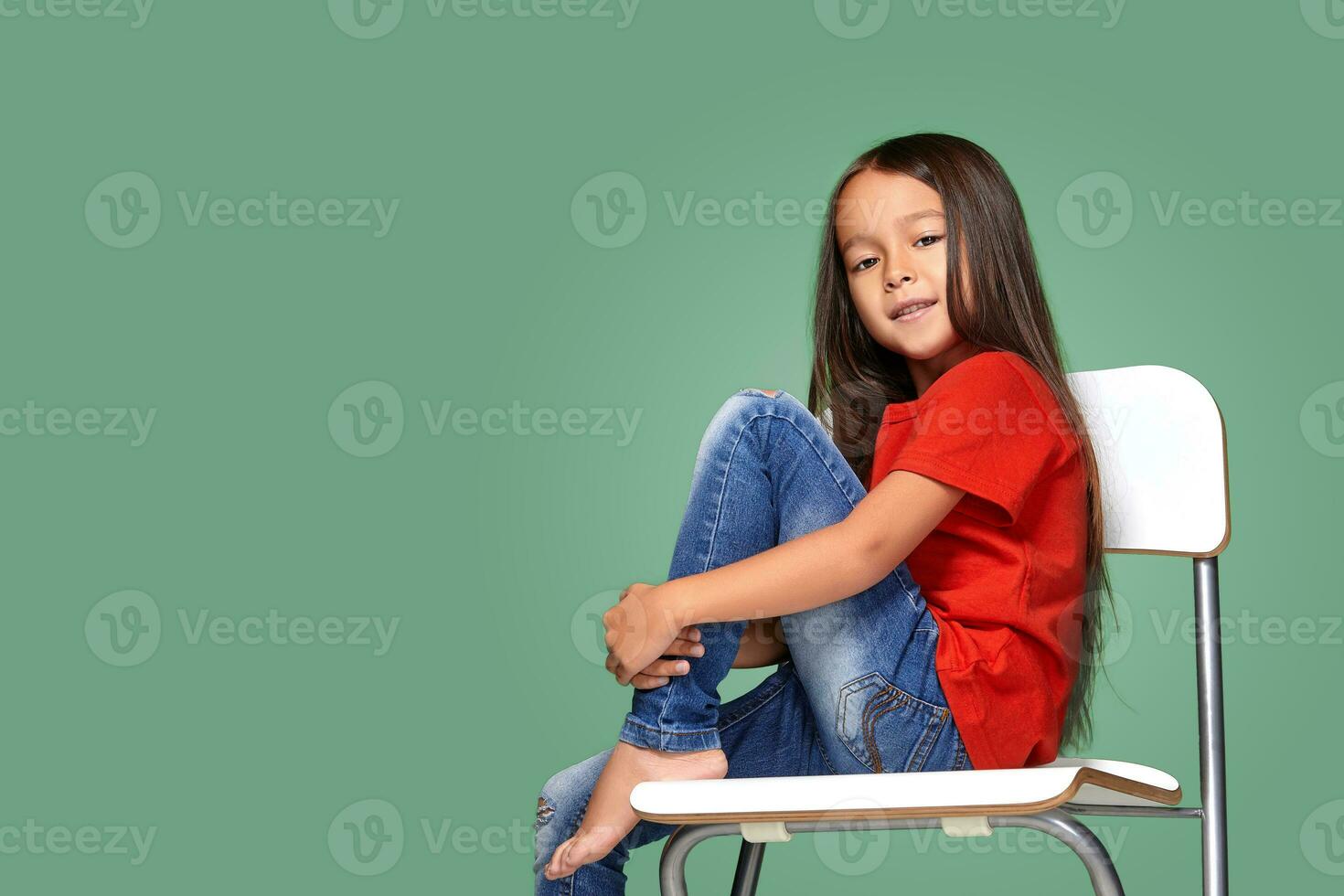 little girl wearing red t-short and posing on chair photo