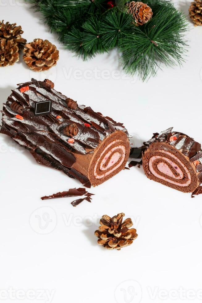 Sliced chocolate sponge cake roll with Christmas tree branch and gilded cones photo
