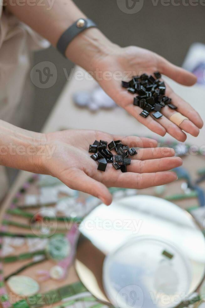 Workplace of the mosaic master women's hands holding mosaic details in the process of making a mosaic photo