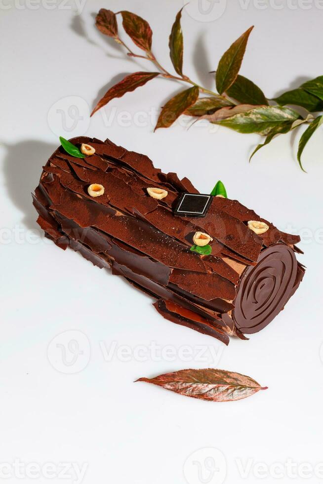 Sweet chocolate cake roll in shape of log with hazelnuts photo