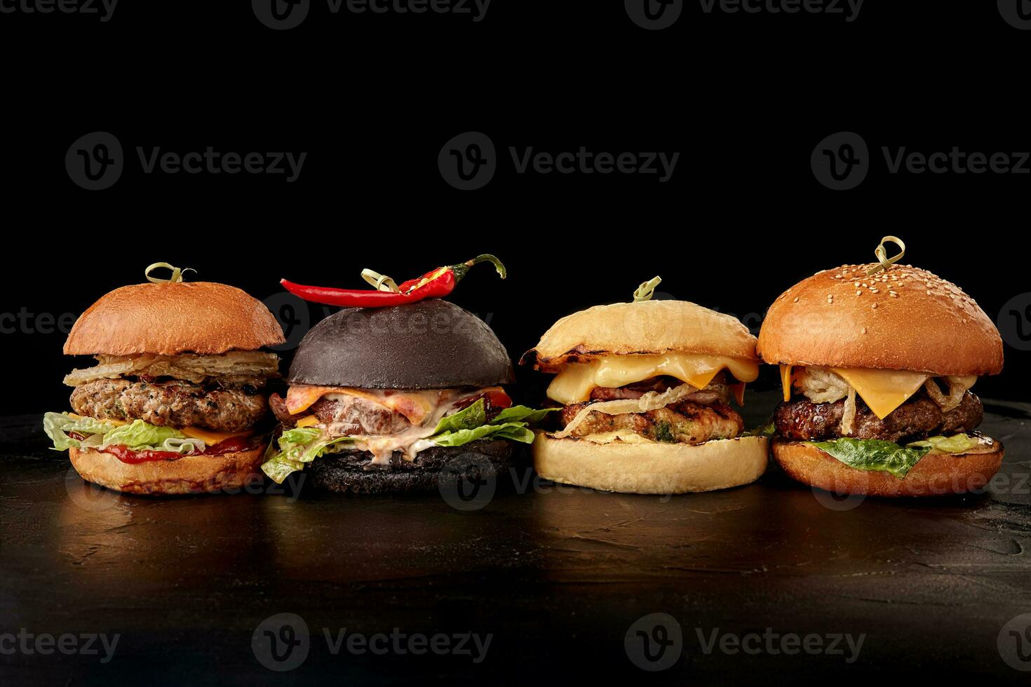 Set of burgers with meat, cheese, tomatoes, mayonnaise on wooden table, black background. Space for text. photo