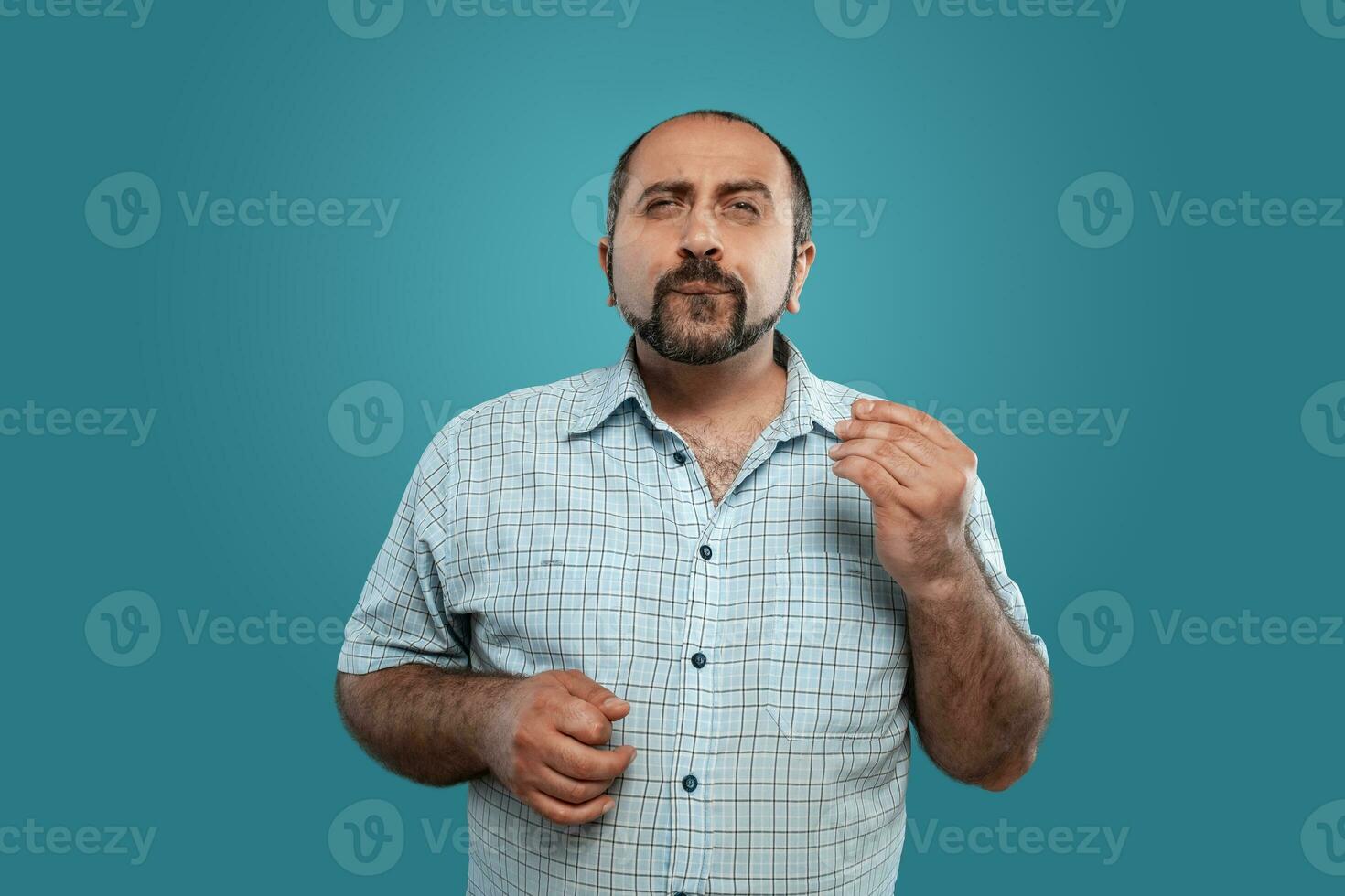 de cerca retrato de un moreno de edad mediana hombre con barba, vestido en un ligero a cuadros camisa y posando en contra un azul antecedentes. foto