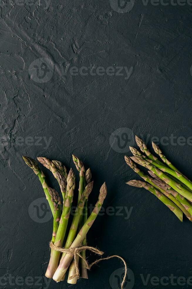 verde espárragos en manojo en negro pizarra antecedentes. atado con yute hilo. sano nutrición, comida y estacional vegetales cosecha. cerca arriba foto