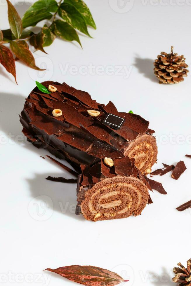 Sliced chocolate cake roll with buttercream and hazelnuts on white background photo