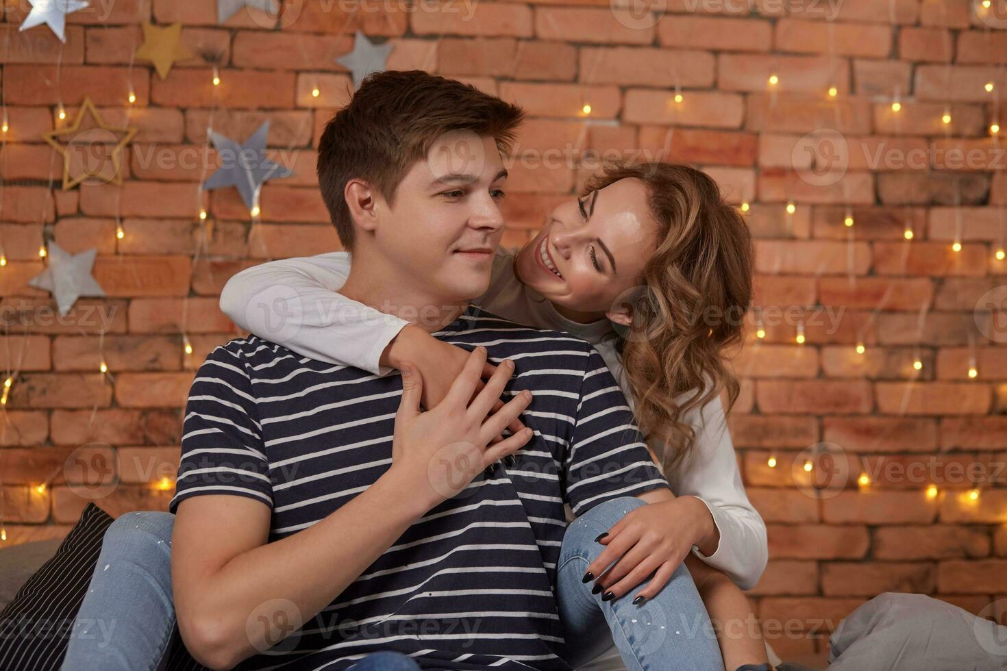 Relation emotions. Young man embracing attractive brunette wife indoor close up photo