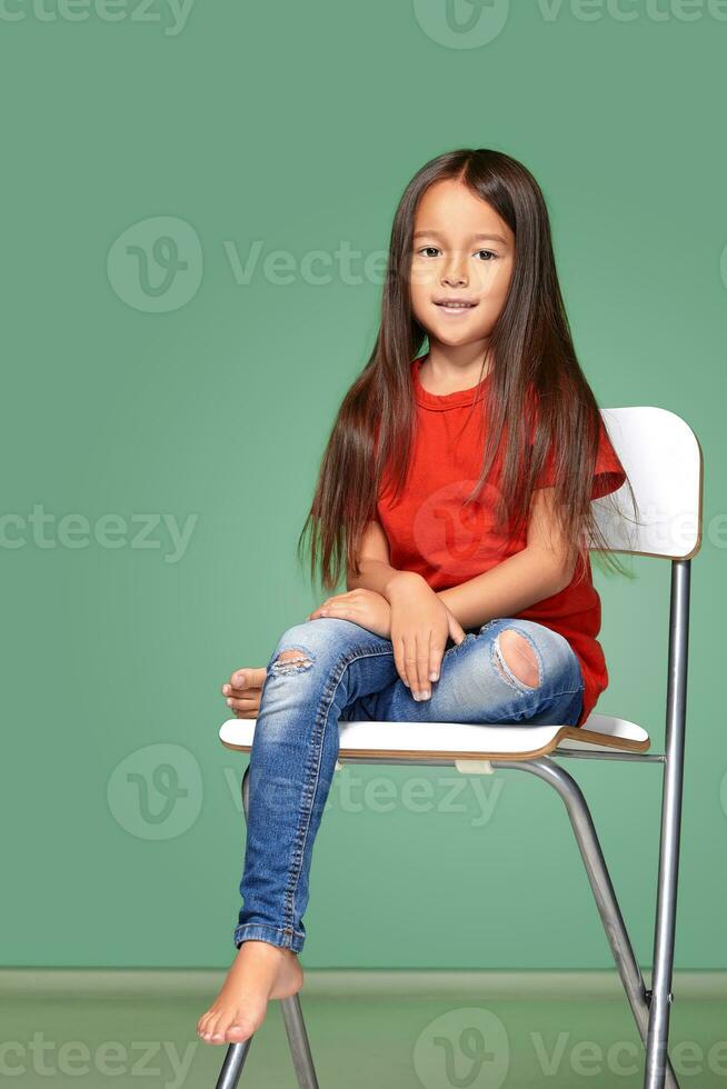 little girl wearing red t-short and posing on chair photo