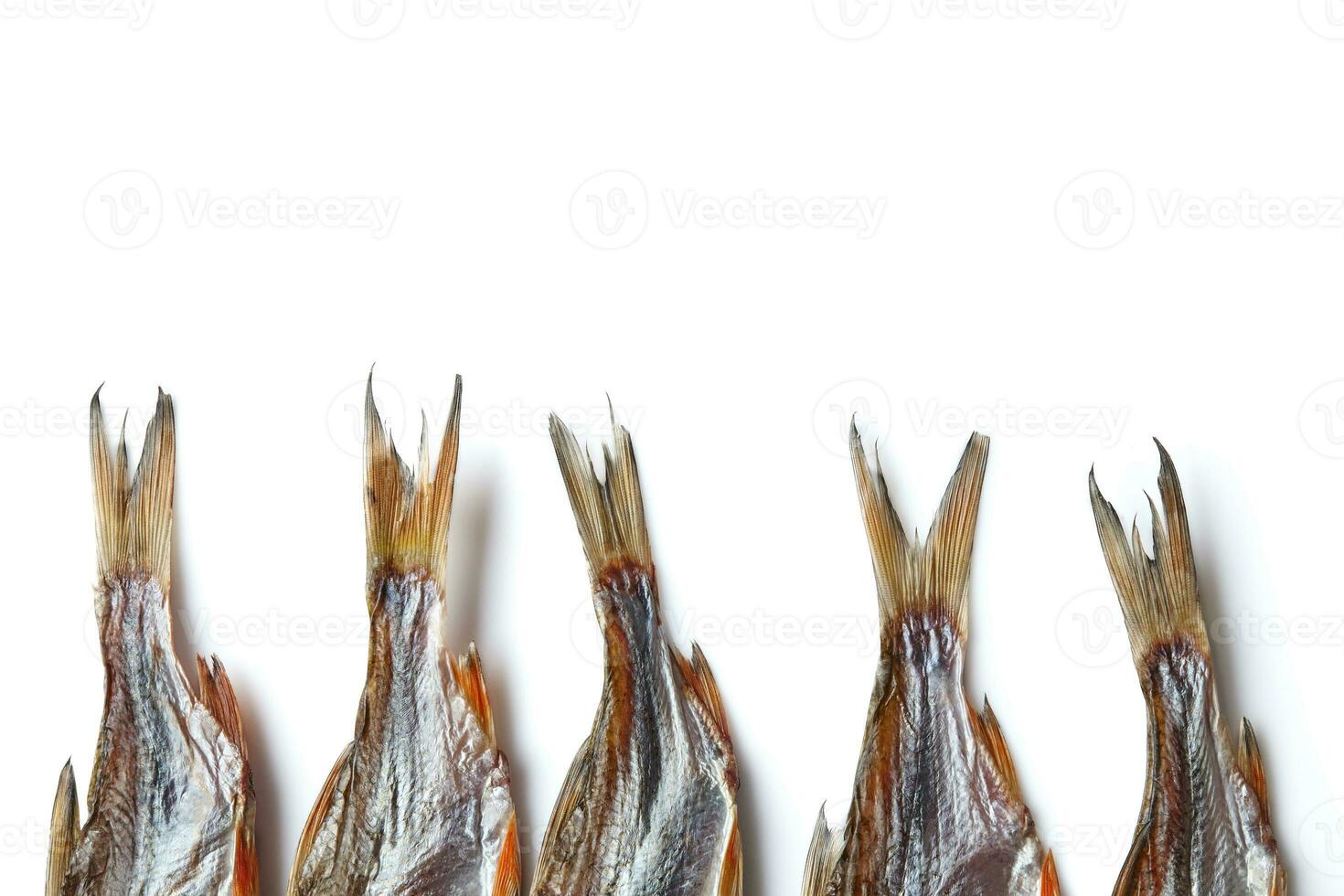 Jerky or dried salted roach tails, clipfish isolated on white background. Beer appetizer. Traditional way of preserving fish. Close up, copy space photo