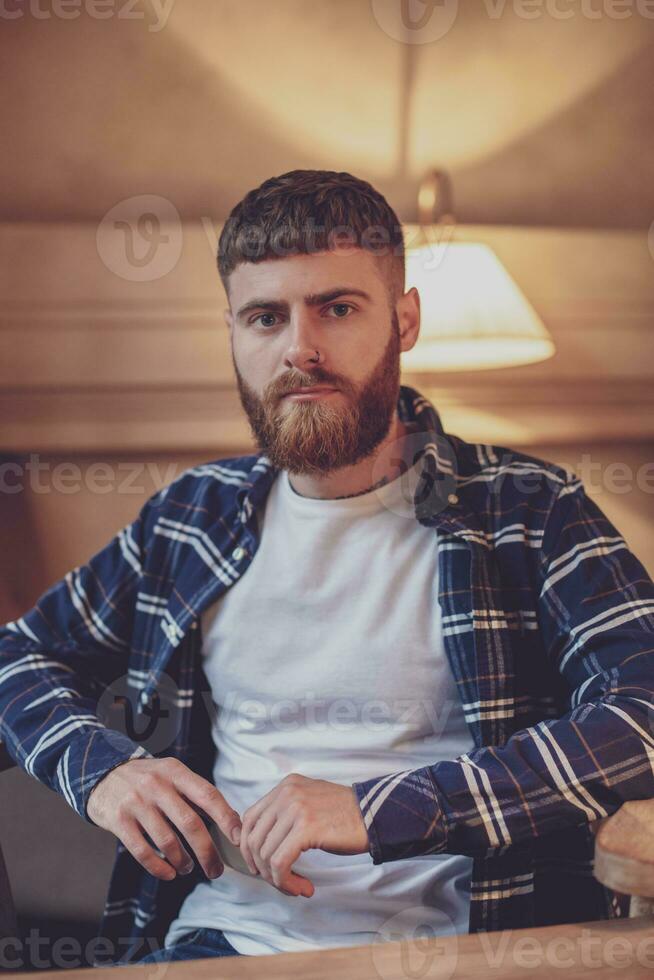 Portrait handsome bearded man wearing plaid shirt at modern cafe photo
