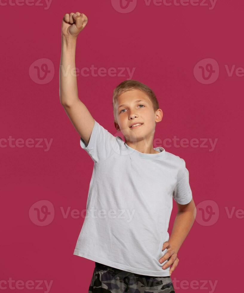de cerca retrato de un rubia Adolescente chico en un blanco camiseta posando en contra un rosado estudio antecedentes. concepto de sincero emociones foto