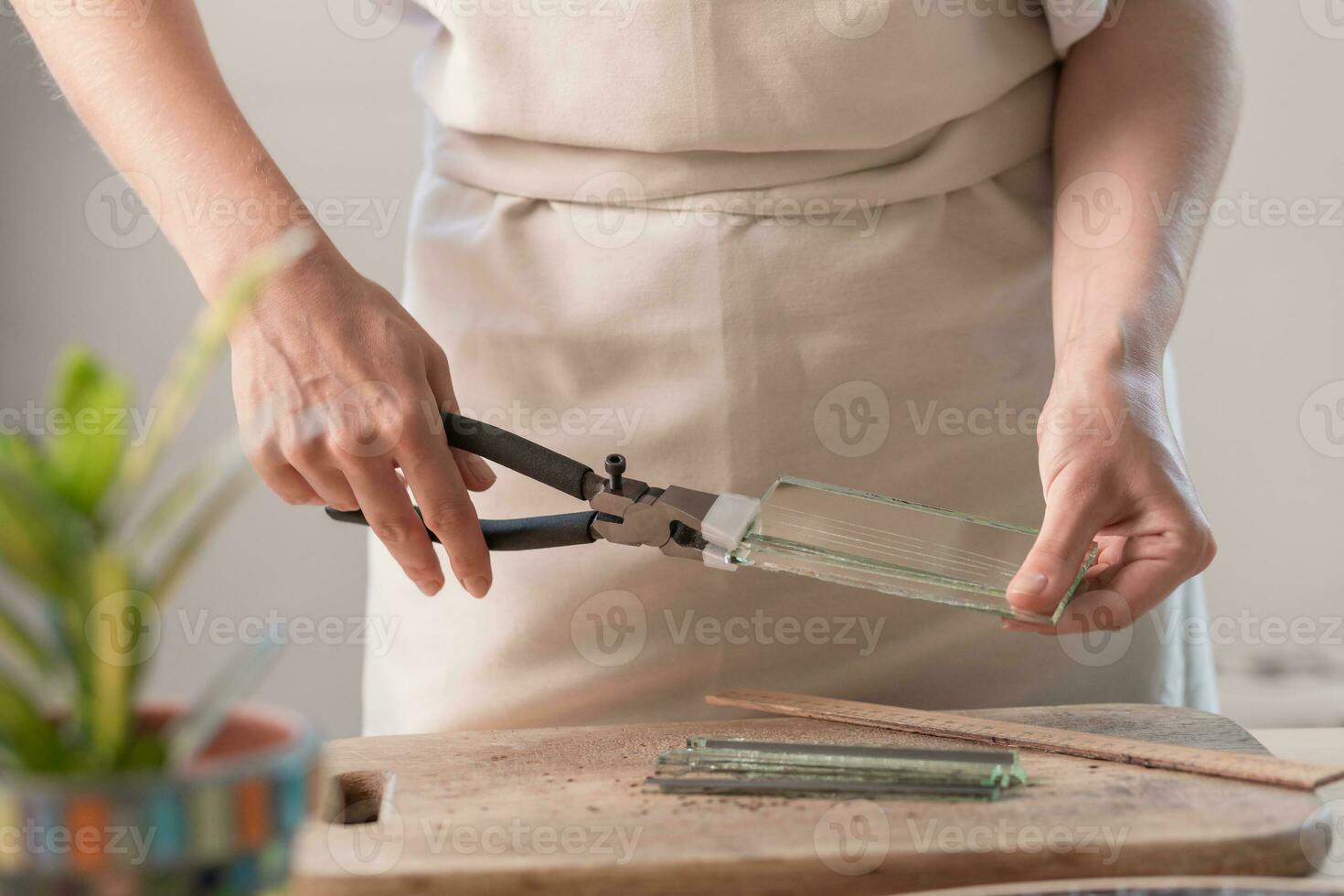 artista corte hojas de manchado vaso dentro pequeño mosaico cuadrícula. de cerca foto