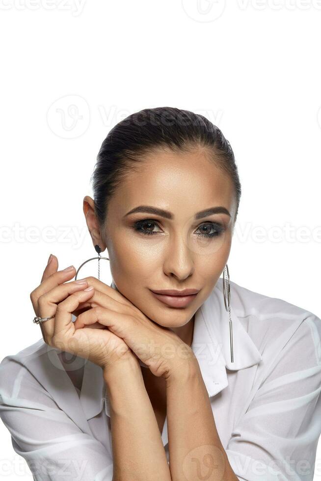 Close up portrait of a brunette model girl with professional evening make-up, wearing a light shirt, posing isolated on white background. photo