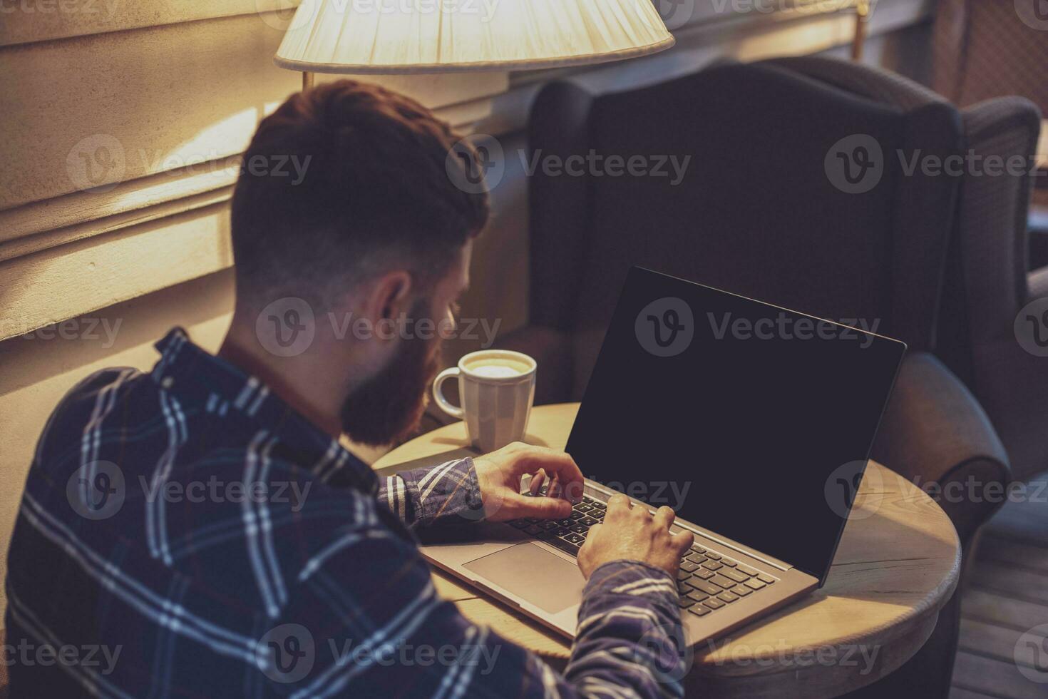 Young man chatting via net-book during work break in coffee shop photo