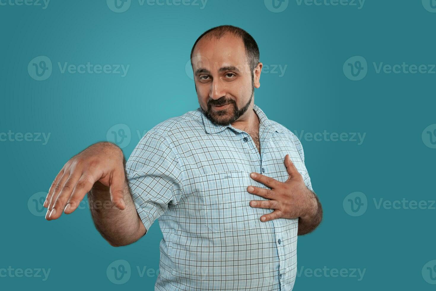 Close-up portrait of a brunet middle-aged man with beard, dressed in a light checkered shirt and posing against a blue background. photo