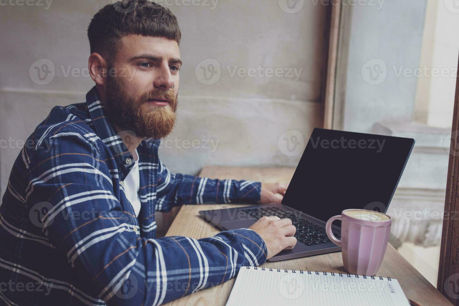 Young man chatting via net-book during work break in coffee shop photo