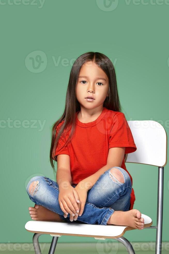 little girl wearing red t-short and posing on chair photo