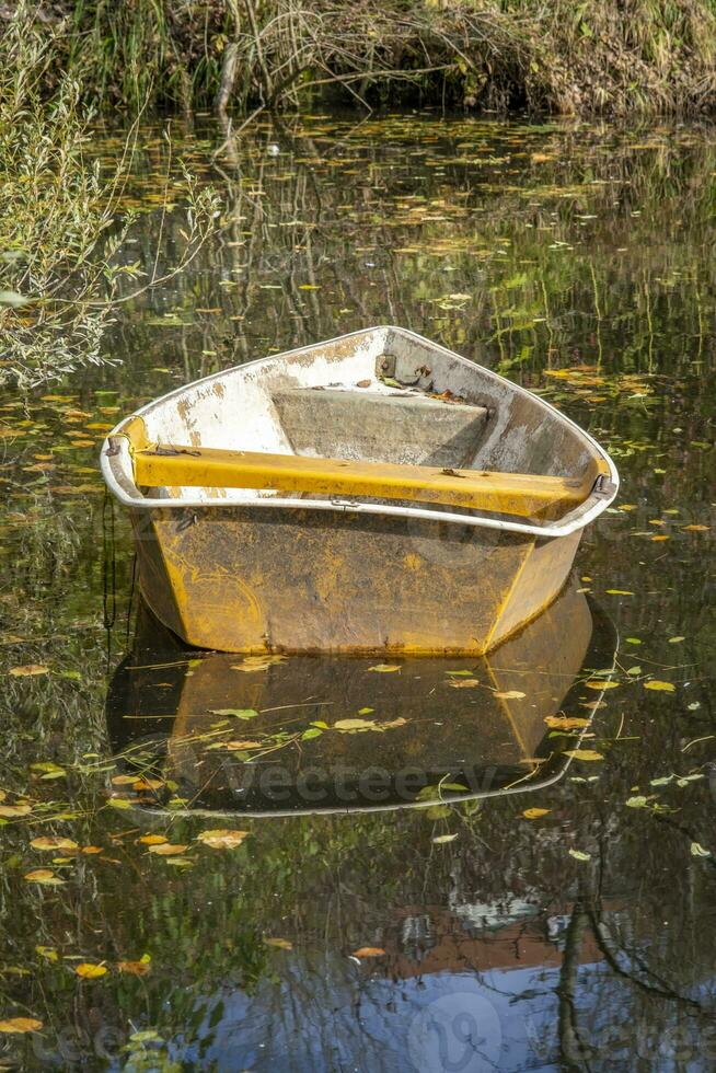 This photos shows a boat on a small pond with reflections in a farmers village in Germany