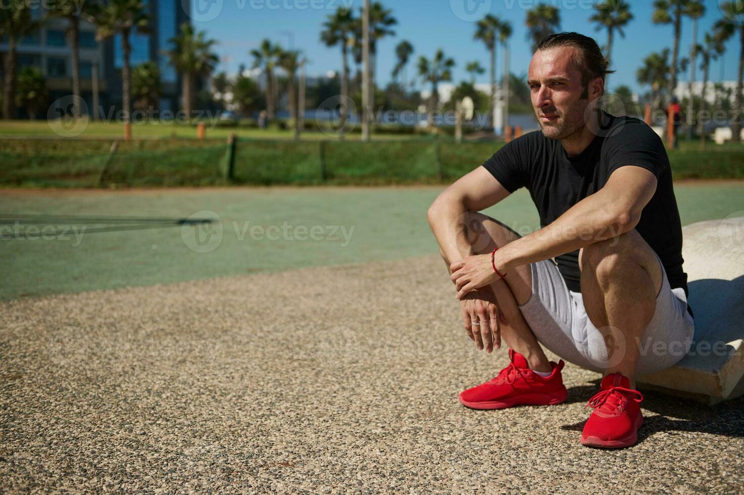 Handsome Caucasian sportsman relaxing after heavy workout in the outdoor urban sportsground. People and sport concept photo