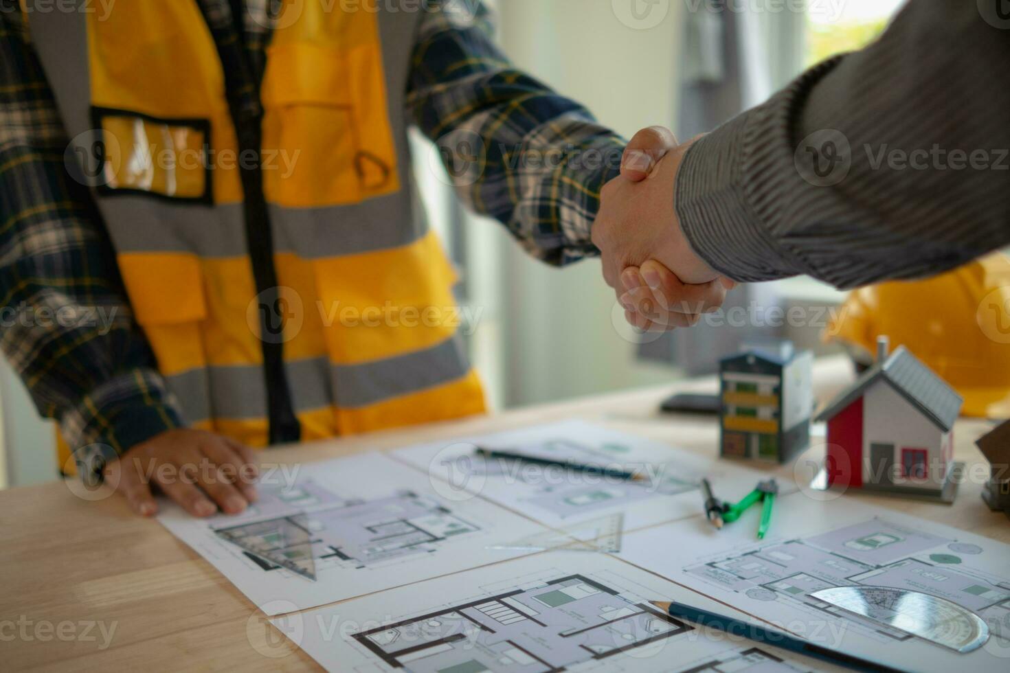 construction engineer joins hands with architect to congratulate housing project that architect team has designed and has been accepted by engineering team. concept of handshake for congratulations photo