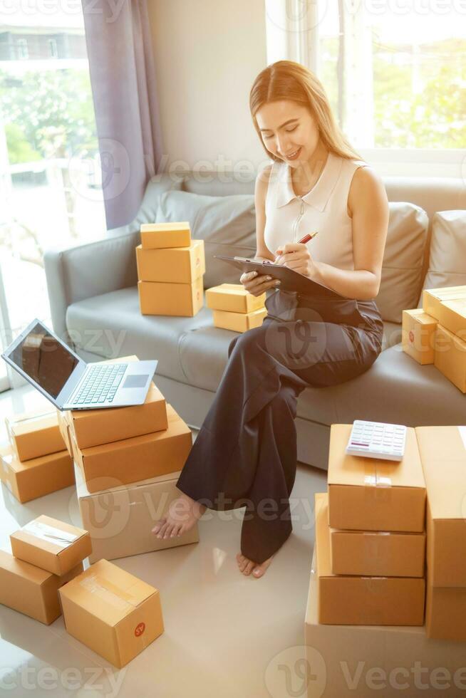 woman checking package of goods from customer online order is alone in her home office as she is an SME entrepreneur and uses her phone and tablet to market online. concept online sales business photo