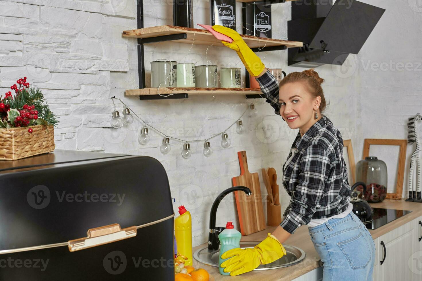 Woman in gloves cleaning furniture with rag at home kitchen. photo