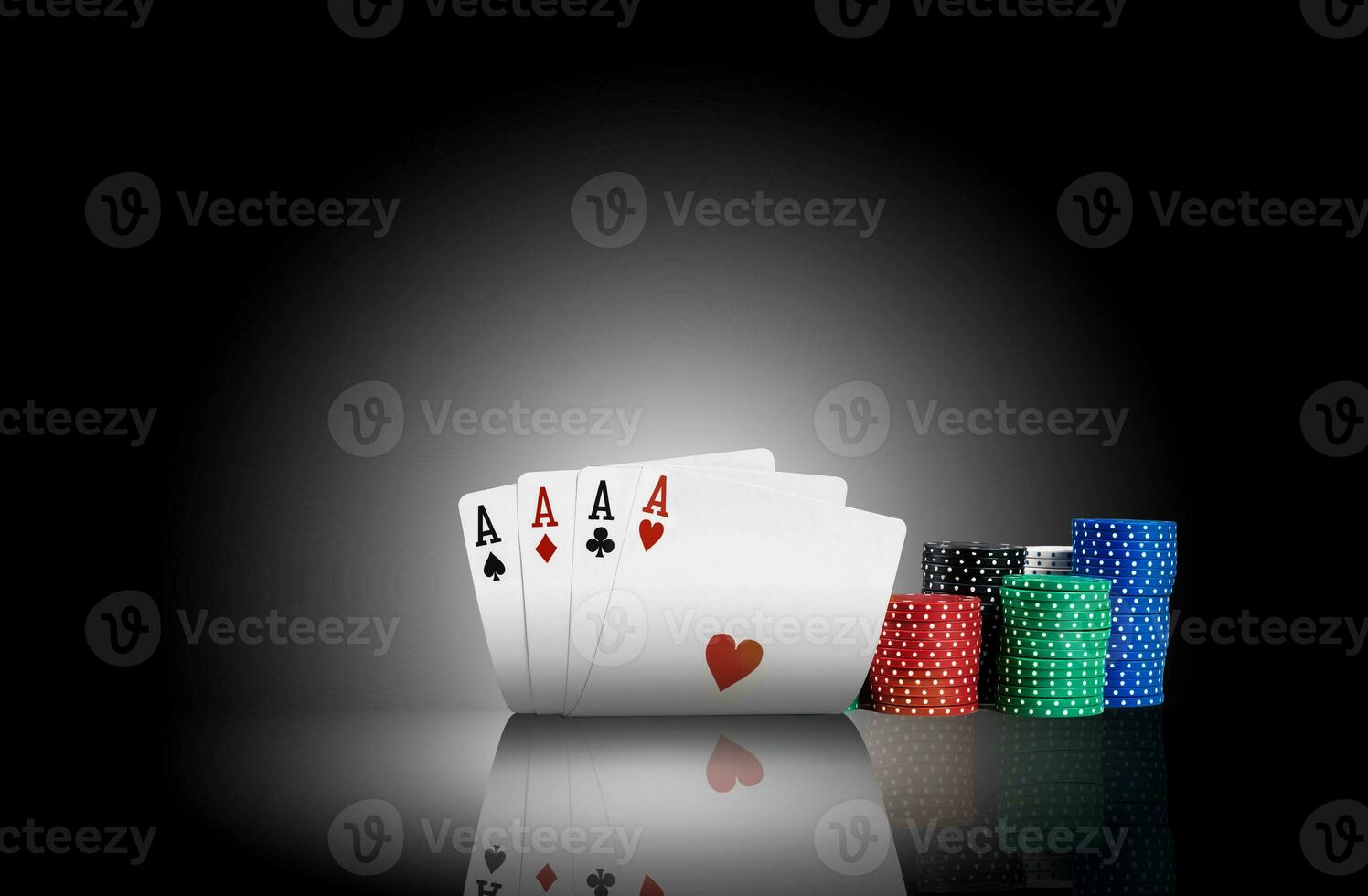 Four aces standing on a mirror surface with a backlight, ahead of a colorful chips in piles. Black background. Gambling entertainment. Close-up. photo