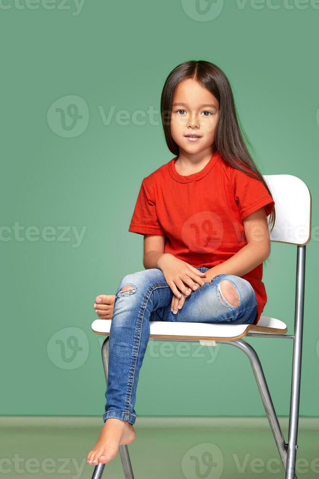 little girl wearing red t-short and posing on chair photo