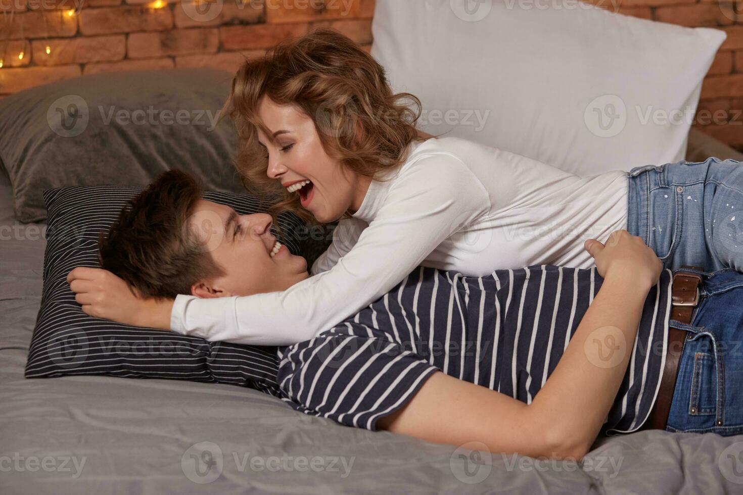 Caucasian young beautiful couple lie on bed and hugging each other photo