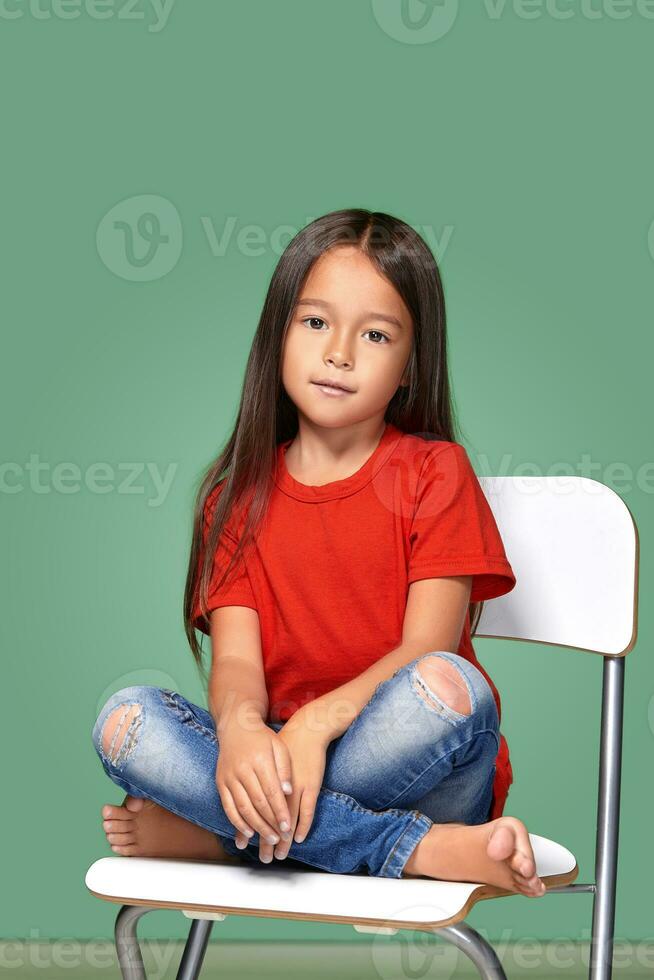 little girl wearing red t-short and posing on chair photo