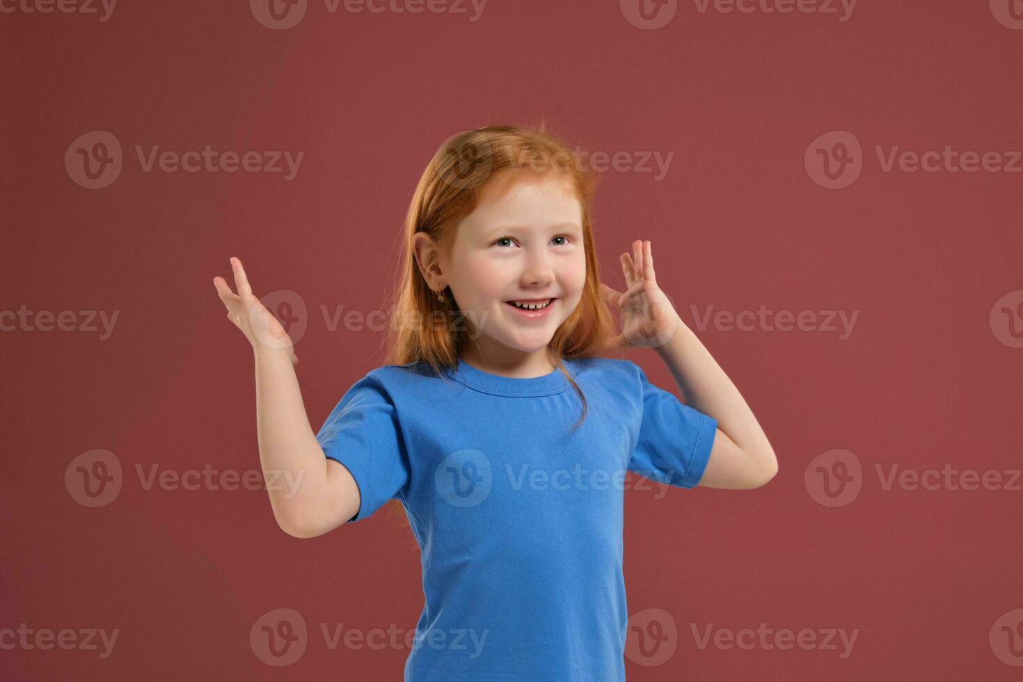 Portrait of cute redhead emotional little girl on red background photo