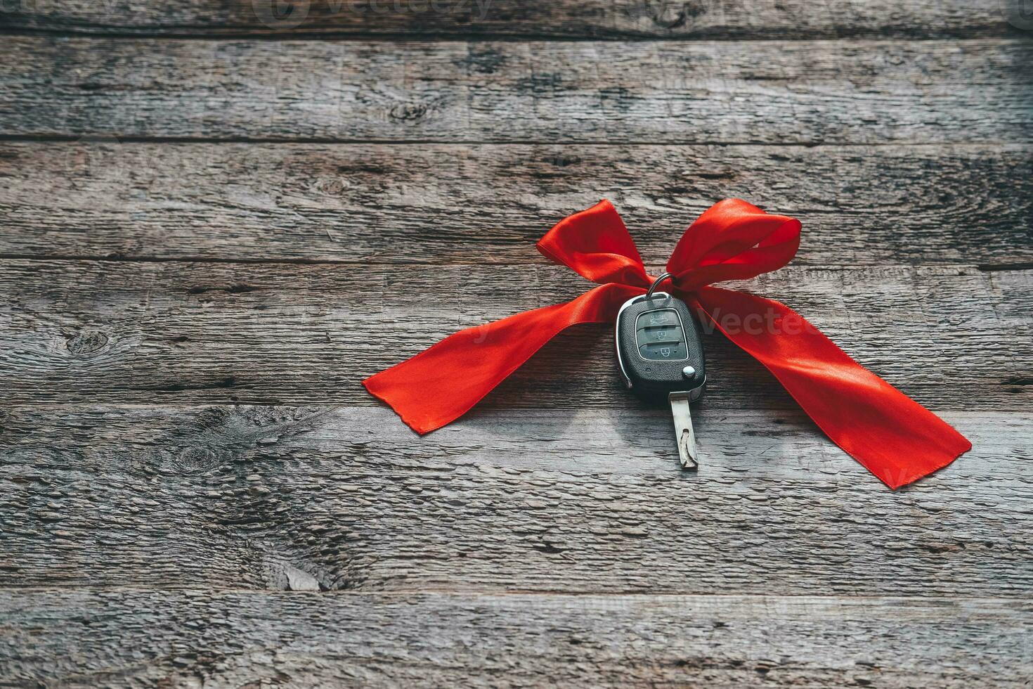 Car keys with red ribbon on a wooden background. The concept of a car gift for the holiday. Valentine's Day. Copy space photo