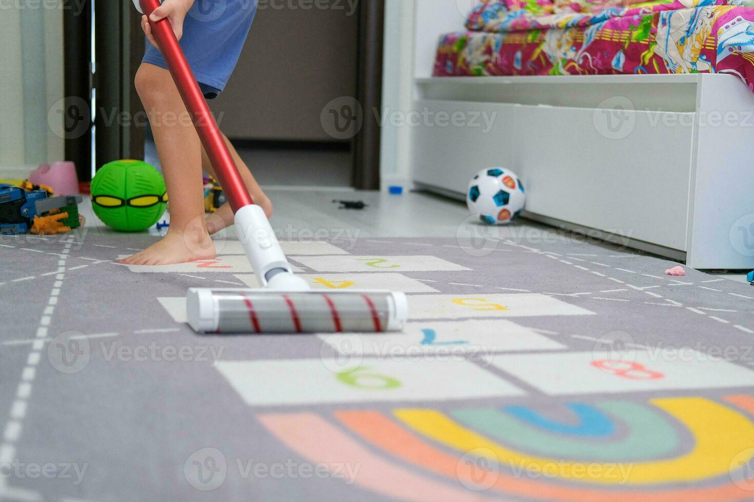 el niño aspiradoras con un sin cable vacío limpiador en el guardería. limpieza en el para niños habitación, Ayudar padres. foto