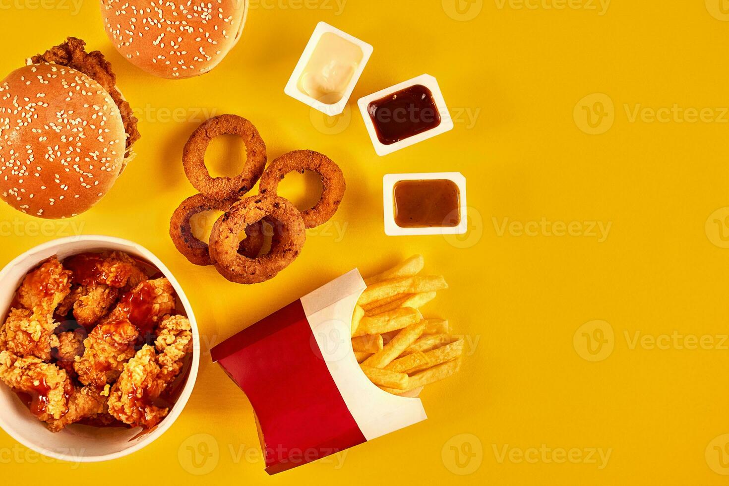 Fast food dish top view. French fries, hamburger, mayonnaise and ketchup sauces on yellow background. photo