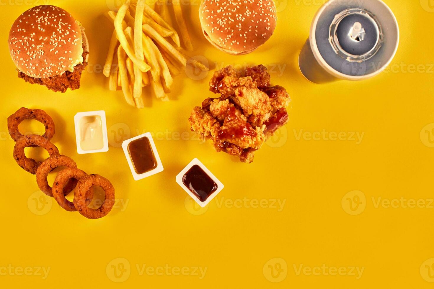 Fast food dish top view. French fries, hamburger, mayonnaise and ketchup sauces on yellow background. photo