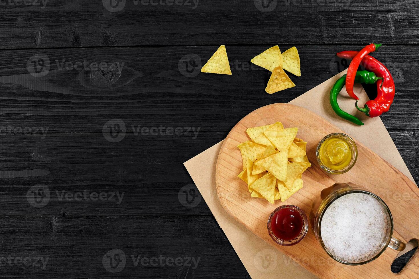 Glass of beer with nachos chips on a wooden background. photo