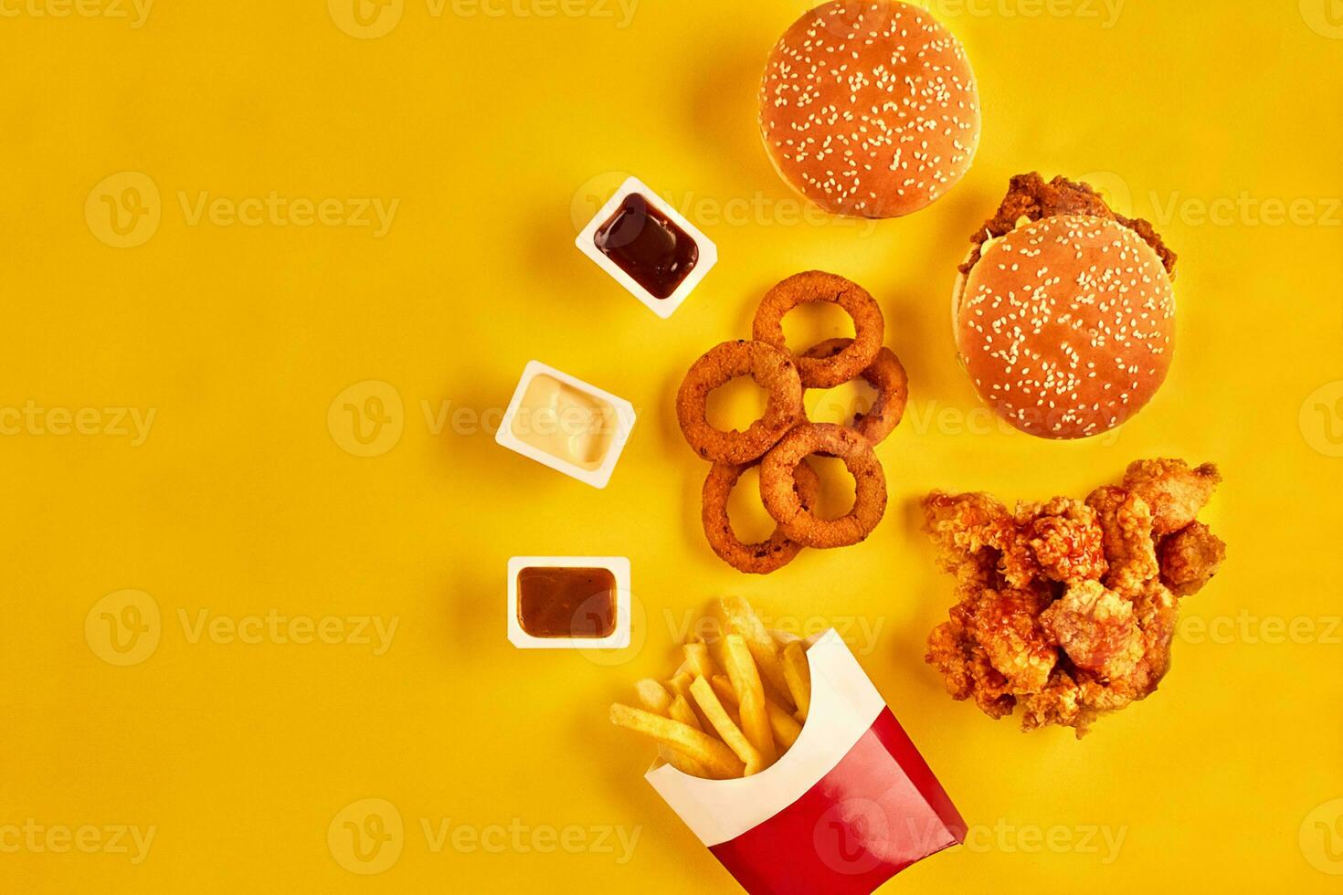 Top view hamburger, french fries and fried chicken on yellow background. Copy space for your text. photo