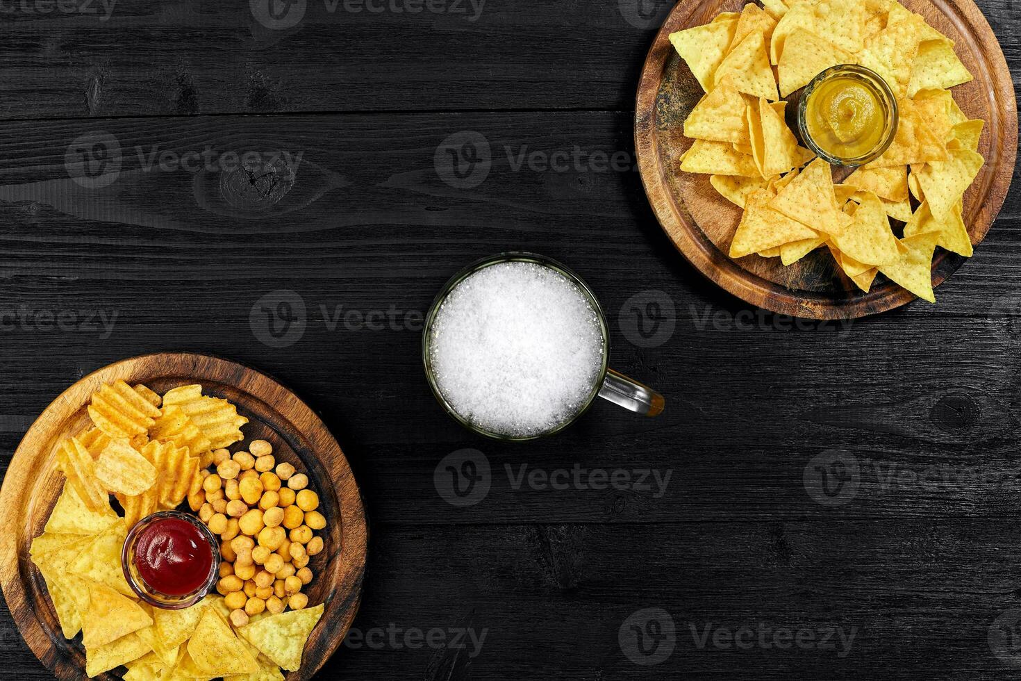 Lager beer and snacks on black wooden table. Nuts, chips. Top view with copyspace photo