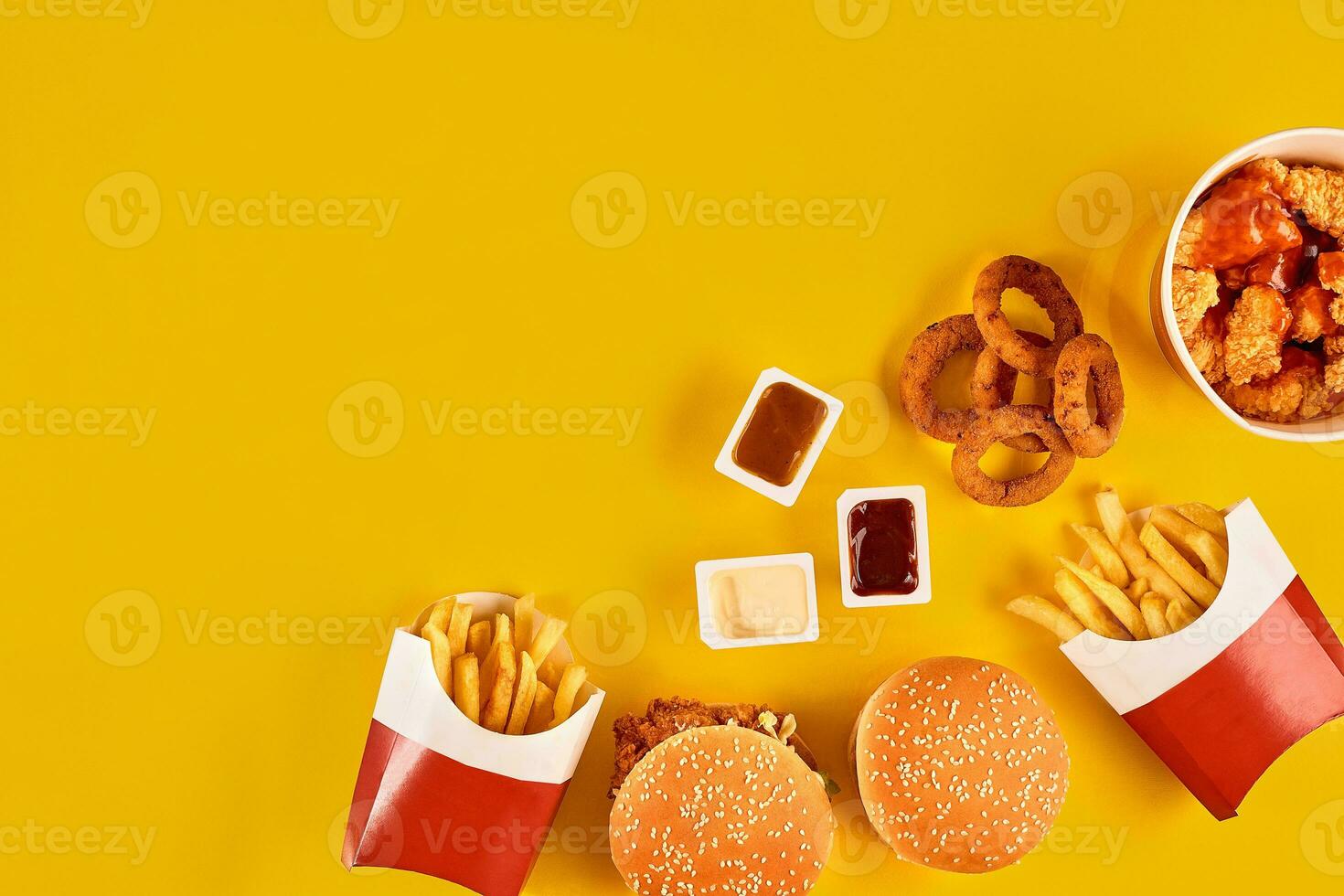 Fast food dish top view. Meat burger, potato chips and wedges. Take away composition. French fries, hamburger, mayonnaise and ketchup sauces on yellow background. photo