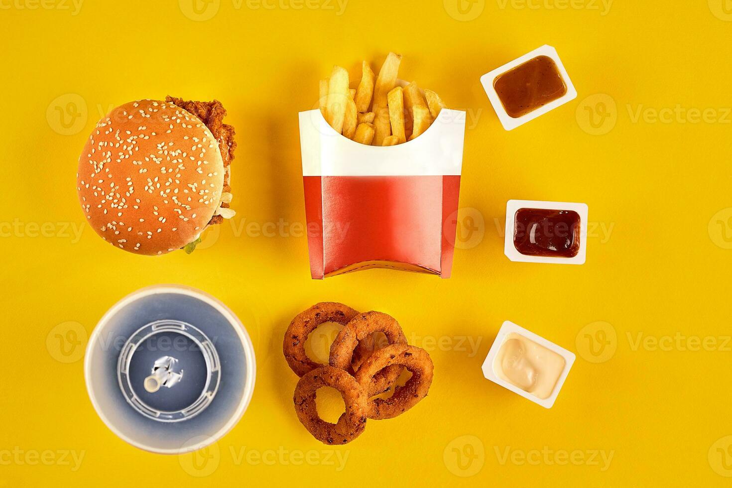 Fast food dish top view. Meat burger, potato chips and wedges. Take away composition. French fries, hamburger, mayonnaise and ketchup sauces on yellow background. photo