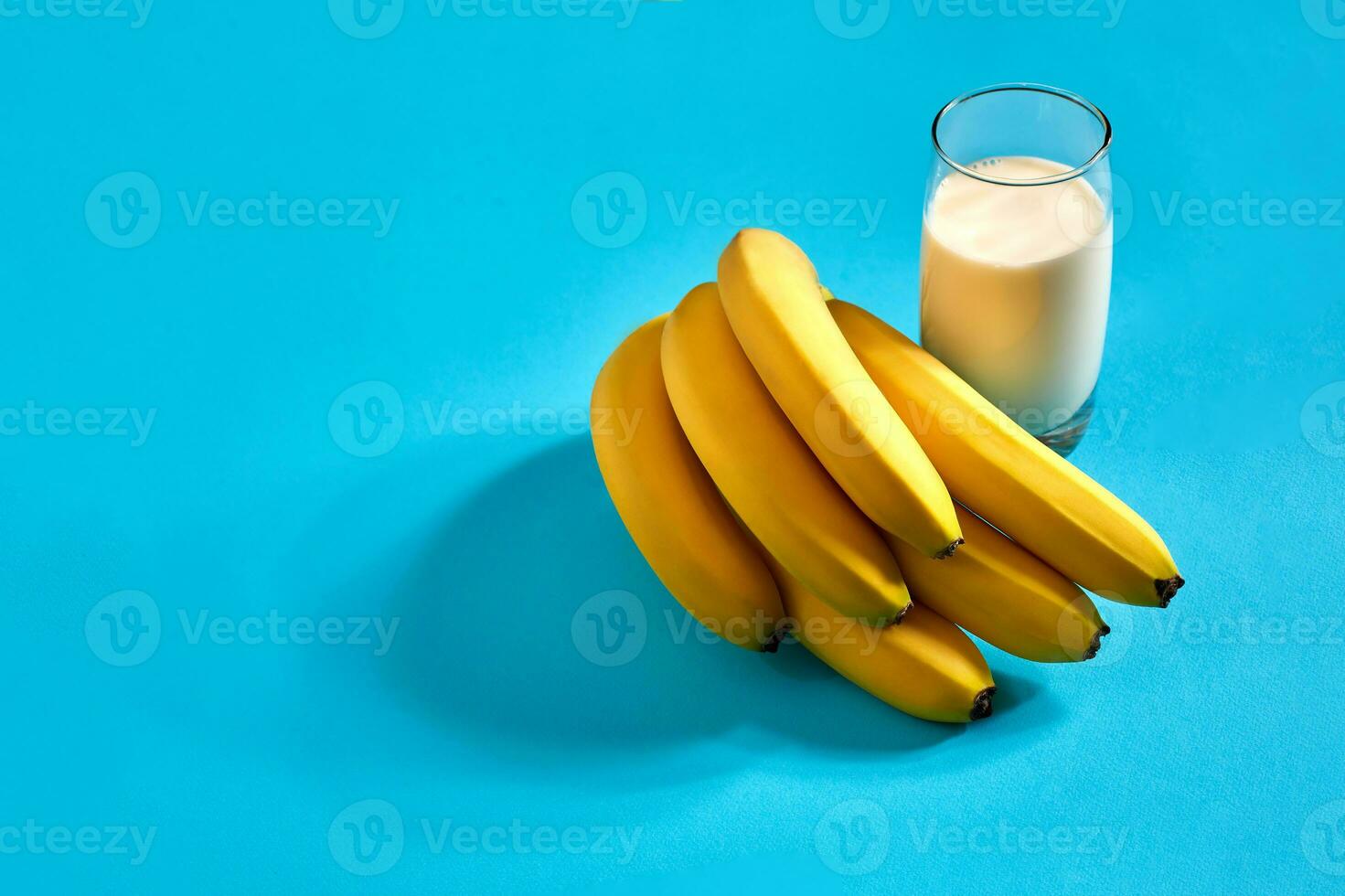 Banana milk drink and a bunch of bananas on a blue background photo